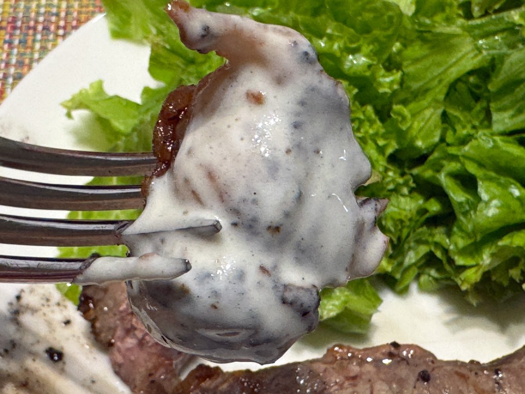 Morceau de steak trempé dans de la sauce Roquefort