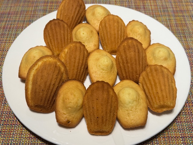 Une assiette avec 16 madeleines, la moitié avec la bosse en haut, l'autre moitié avec le côté cannelé en haut.