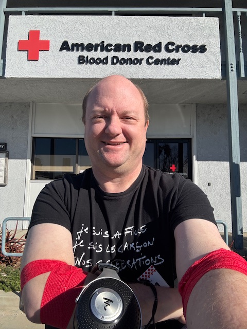 Photo de l'auteur après le don, avec un pansement sur chaque bras