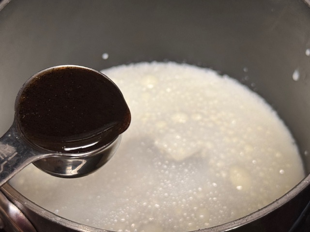 Cuillère de vanille en haut de casserole pleine de lait