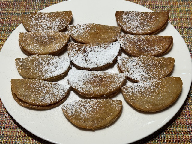 Une assiette de 12 dizé milé, des beignets fourrés de crème pâtissière au rhum, dont la pâte est parfumé de citron vert, muscade, amande amère et cannelle. 