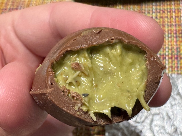 Œuf en chocolat découpé en deux pour montrer la garniture à la pistache là-dedans. 