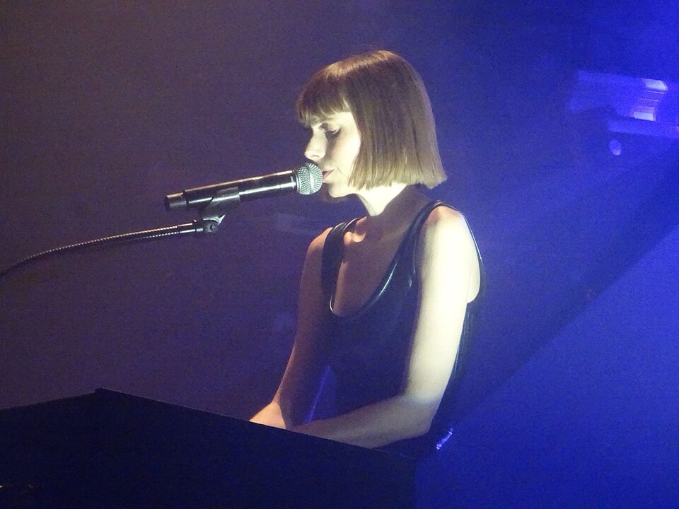 Photo de Marie-Flore en concert, débout devant un clavier et un micro.