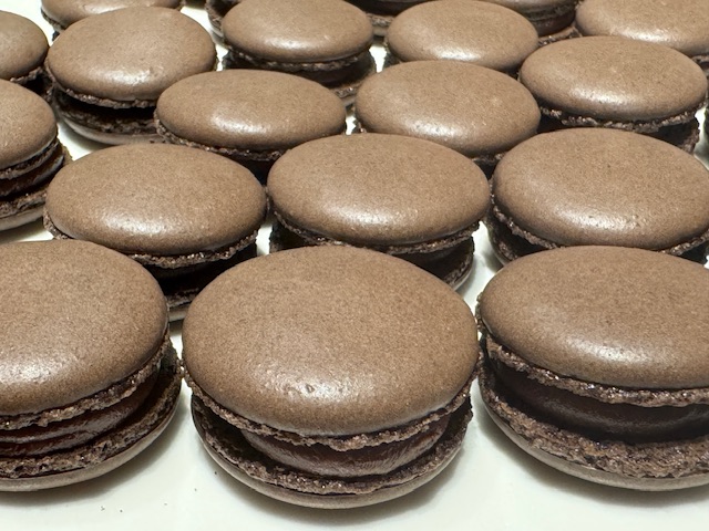 Un lot de macarons au chocolat en gros-plan. Les coques sont sans fautes-- ni bulles ni bosses.
