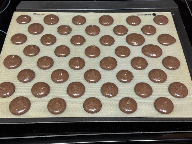 Premier lot de coques au chocolat après avoir tapé la plaque sur le four pour retirer des bulles