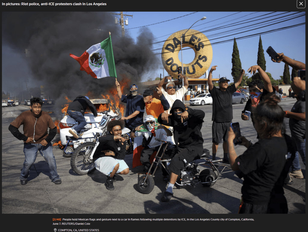 Un groupe d'une dizaine de hommes assis dans la rue devant Dale's Donuts. Ils portent des drapeaux mexicains. Un homme porte un keffiyeh sur la tête.