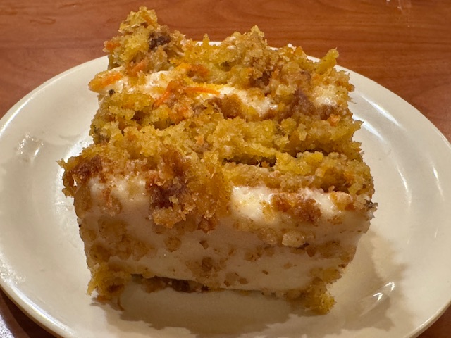 Carrot cake avec deux couches de gâteau, deux couches de glaçage au fromage Philadelphia, et recouvert de noix écrasées.