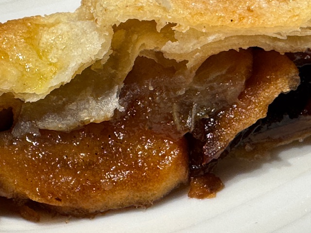 Tranche de la croustade en gros-plan, pour voir sa garniture de pommes, de poires et de pruneaux