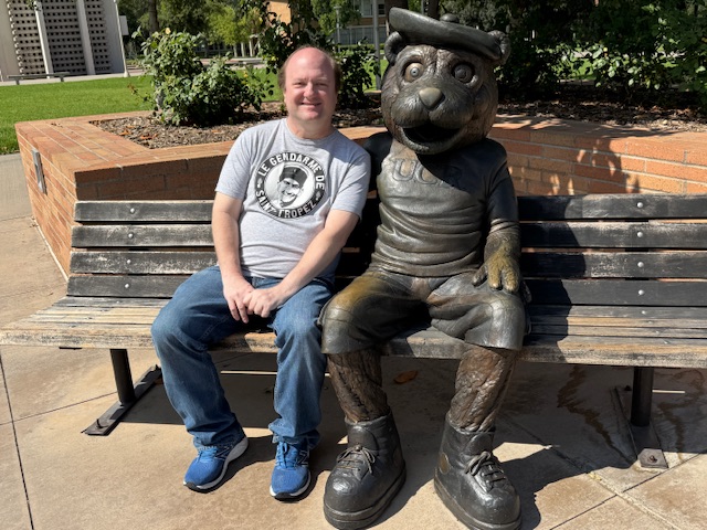Moi avec une sculpture d'un castor assis sur un banc