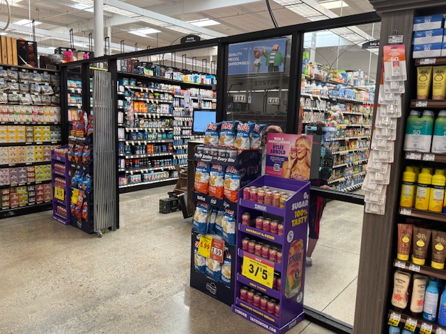 Des portes en verre installées devant les rayons de médicaments en vente libre et de lessives.