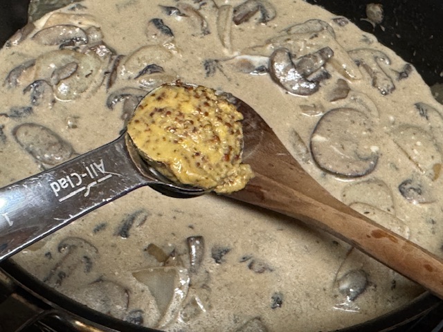 Cuillère à café de moutarde posée sur la poêle