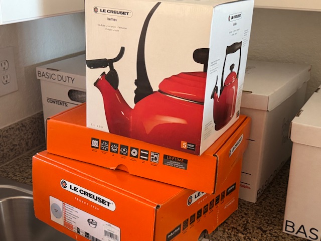 De bas en haut : carton d'une cocotte de 6,75 L, carton d'une poêle en fonte émaillée, carton d'une théière 