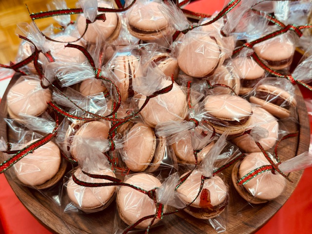 3 douzaines de macarons aux fraises, emballés individuellement et attachés avec un ruban rouge et vert pour Noël.