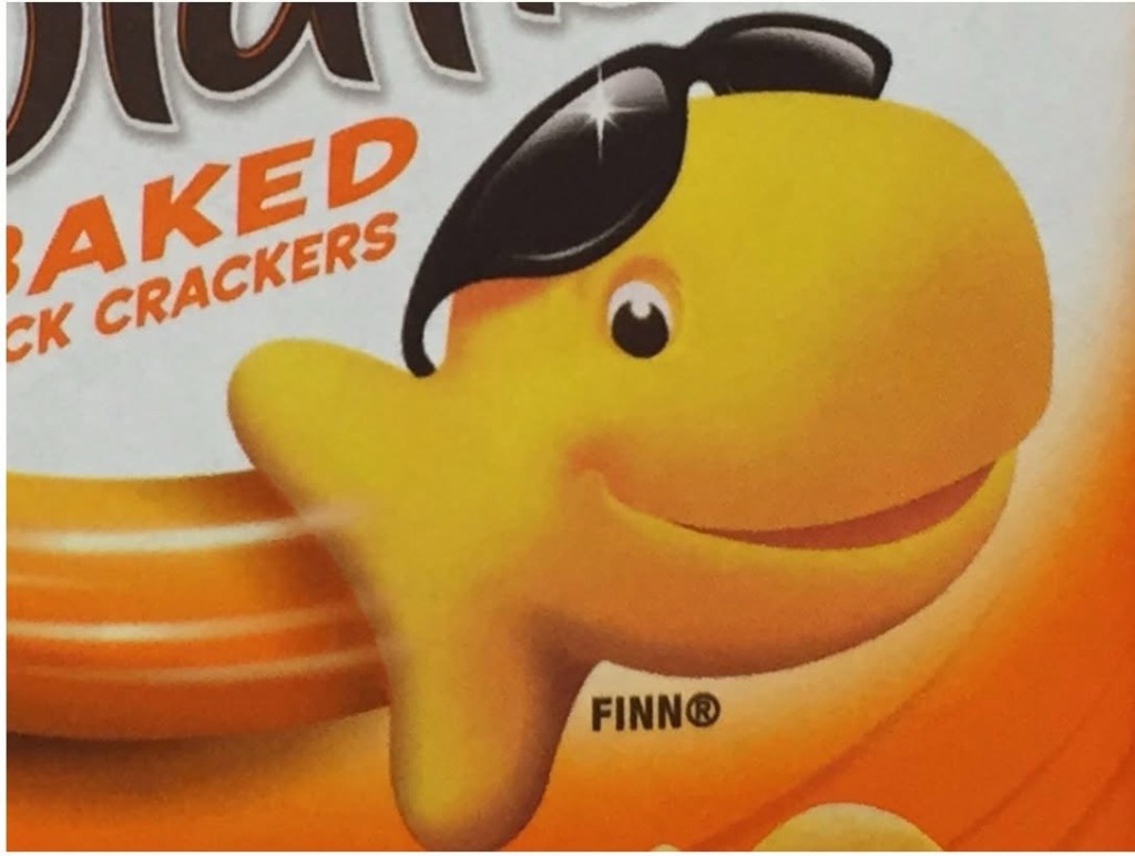 C'est un biscuit Goldfish -- jaune, et en forme de poisson rouge sans détails -- avec un grand sourire. Il porte des lunettes à soleil, mais sur ses yeux, qui restent visibles.
