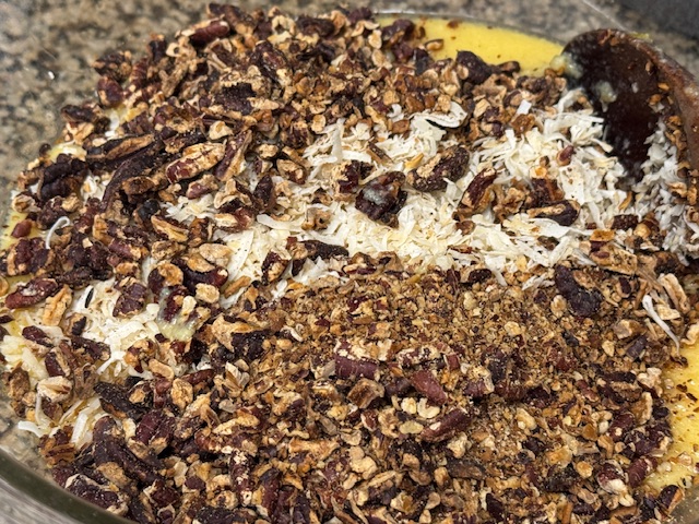 Glaçage versé dans un saladier avec la noix de coco et les noix de pécans