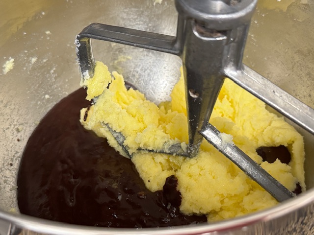 Chocolat fondu ajouté au beurre/sucre. Le mélange semble flotter sur le chocolat.
