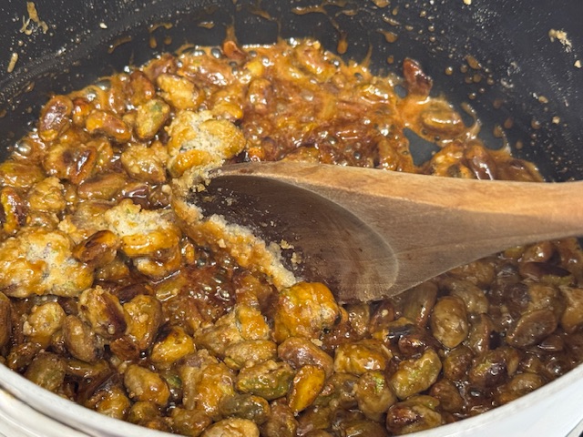 Sucre en train de caraméliser. La moitié des pistaches est recouverte d'un liquide brun