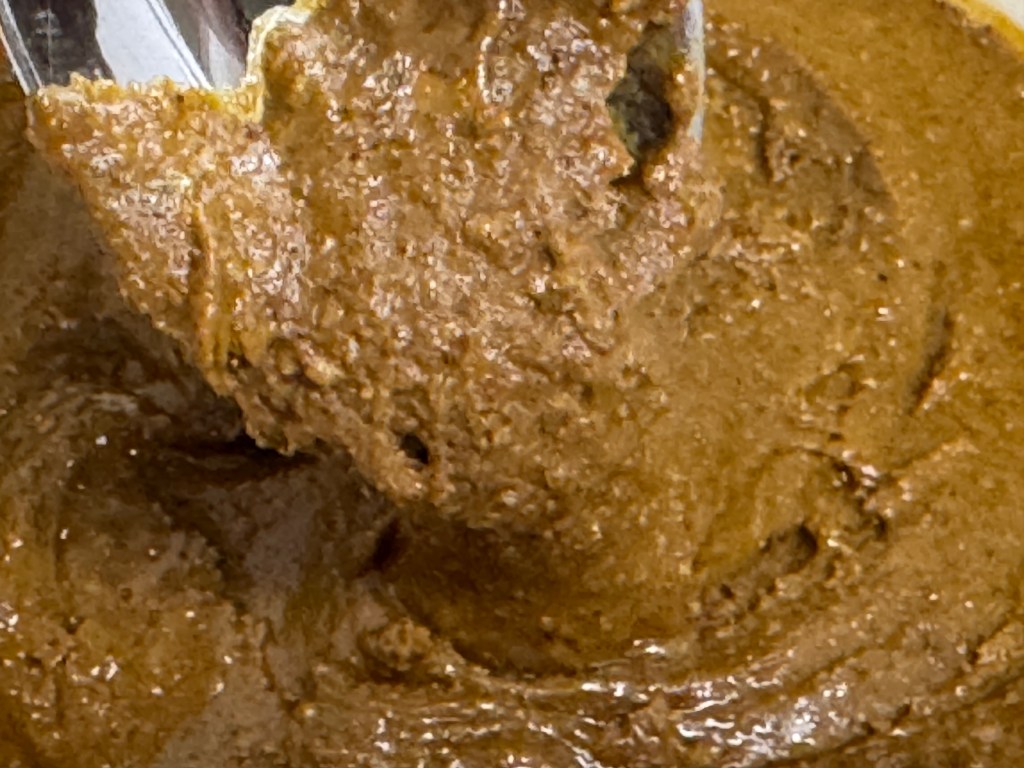 Praliné en très gros plan, coulant très, très lentement d'une cuillère en inox