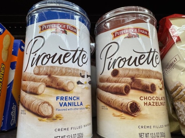 Deux boîtes rondes de biscuits Pirouettes : à gauche, « Vanille française » (pas parfumé avec de vraie vanille selon les caractères petits), à droite, chocolat-noisette