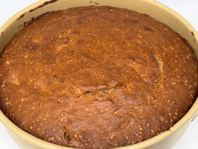 Gâteau sorti du four, toujours dans le moule ; il y a une petite fente au centre où le point du couteau a été testé