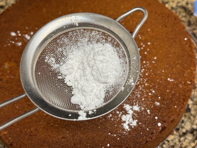 Petit tamis au-dessus du gâteau, rempli de sucre glace