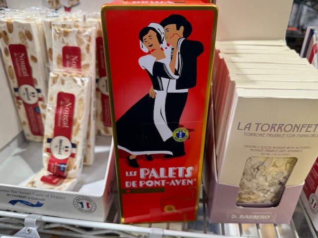 De petites boites rouges de palets de Pont-Aven, avec un dessin d'un couple qui danse. Du nougat entoure les palets.