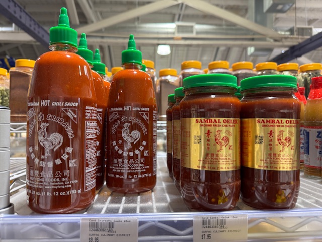 Deux genres de sauce piquante asiatique. La sriracha est dans une boîte grande mais de largeur étroite, avec des bouchons verts en plastique. 