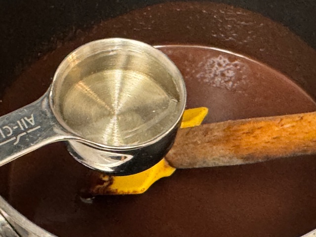 Cuillère à soupe pleine de sirop de glucose tenue sur la casserole