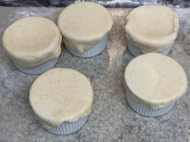 Il y a 5 ramequins, chacun recouvert de pâte feuilletée.