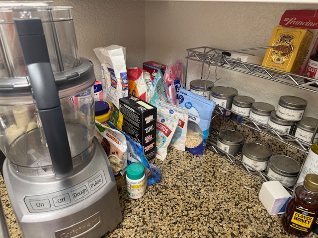 Comptoir à gauche du four -- il y a de nombreux sacs d'ingrédients : farine, sucre, fruits de coque, etc.