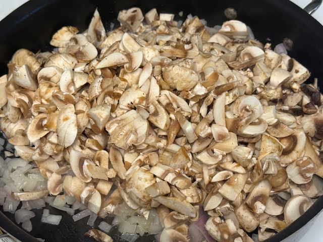 La moitié des champignons ajoutée aux échalotes