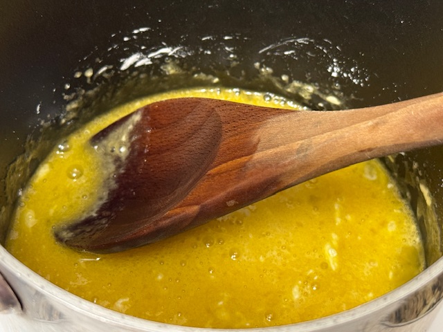 Mélange des ingrédients dans la casserole, avec une cuillère en bois au centre