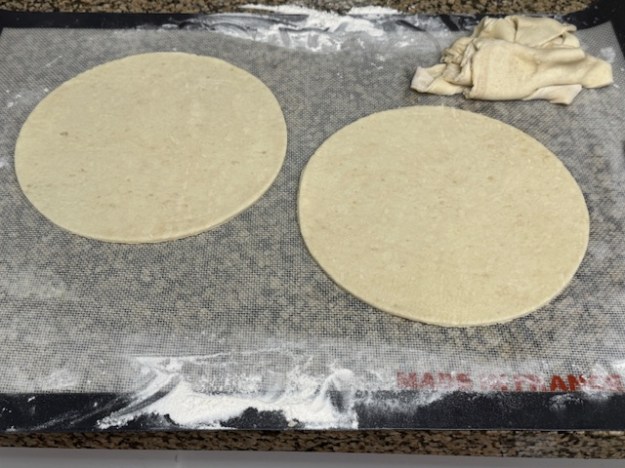 Deux cercles de pâte sur le plan de travail. Des restes sont visibles en haut à droite