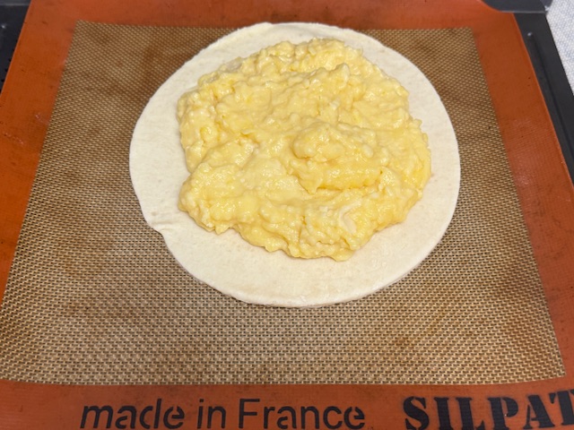 Disque de pâte avec l'appareil au centre, en forme de cercle, avec des bords de 2 cm