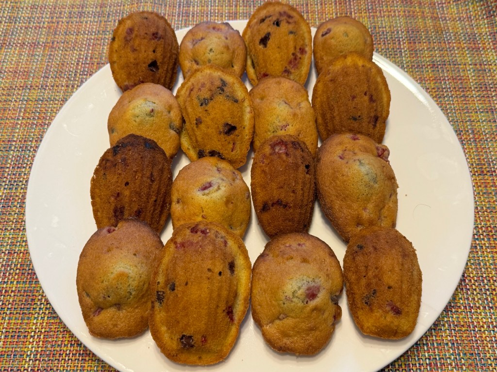 16 madeleines avec des pépites de chocolat et des morceaux de framboise partout. Elles sont arrangées en 4 rangs de 4 chacun, où la moitié ont la bosse en haut, et l'autre moitié, le côté coquillage.