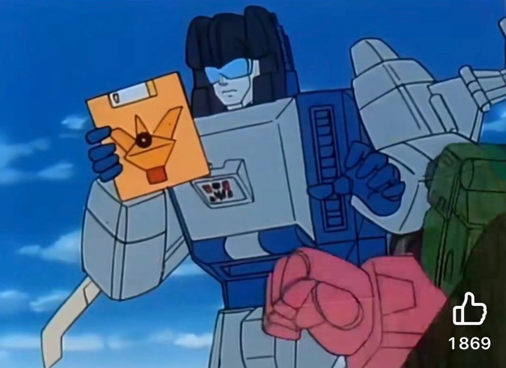 C'est un Transformer inconnu pour moi qui tient dans la main une disquette de 3,5 pouces, mais apparemment plus grande vu sa taille par rapport au robot.