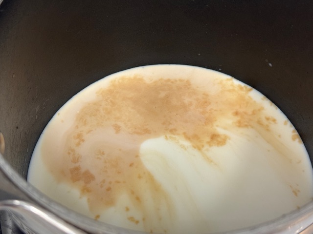 Vanille visibilement brun flottant sur le lait dans la casserole
