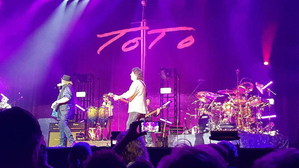 C'est une photo du groupe Toto sur scène -- le nom est en arrière-plan -- à Middelkerke en Belgique