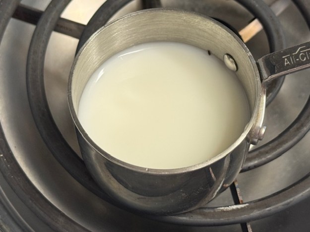 Tasse de lait et d'eau posée sur la bobine d'une cuisinière électrique.