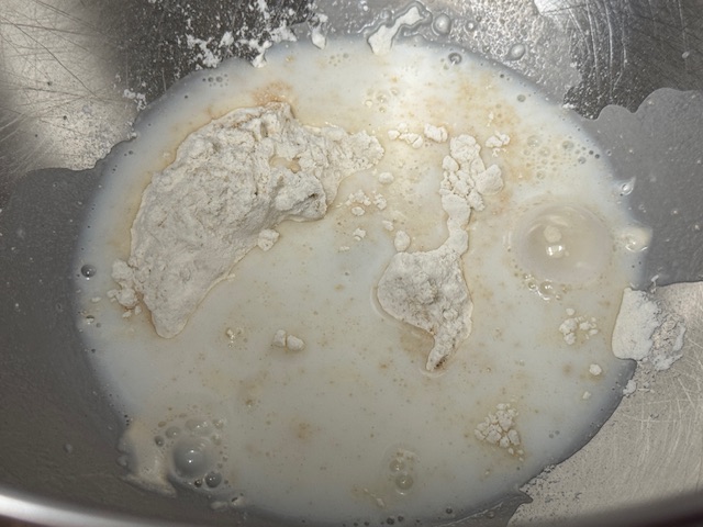 Lait versé sur la farine et la levure ; des grumeaux flottant partout