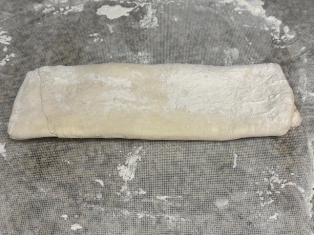 Pâte feuilletée maison sur un plan de travail fariné.