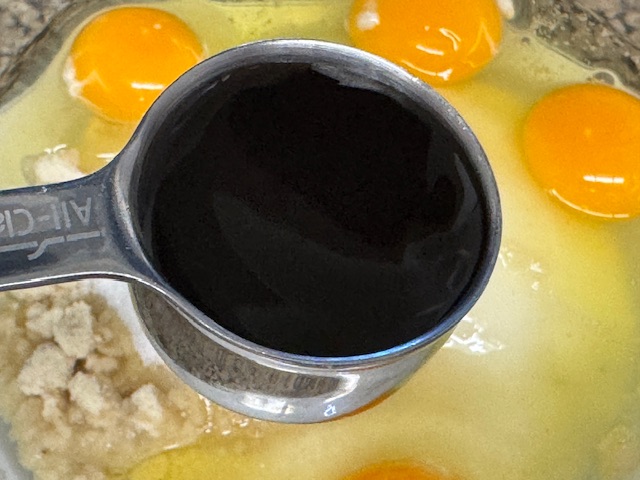 Cuillère à soupe en métal pleine de pâte de vanille, posée au-dessus d'un saladier.