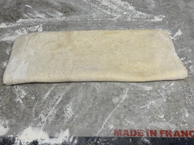 Pâte feuilletée sur un plan de travail fariné.