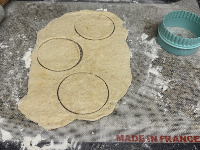 Trois ronds coupés des restes, avant d'être retirés. L'emporte-pièce est à droite de la pâte