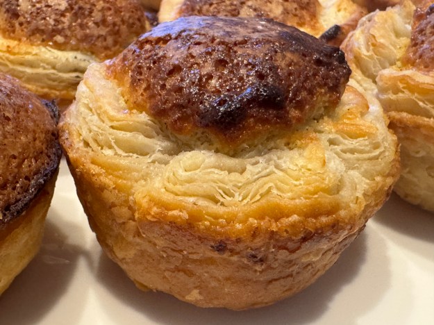Un mirliton en gros-plan, avec d'autres visibles aux bords de la photo. Il n'y a pas encore du sucre glace, ce qui permet de voir le feuilletage de façon détaillée.
