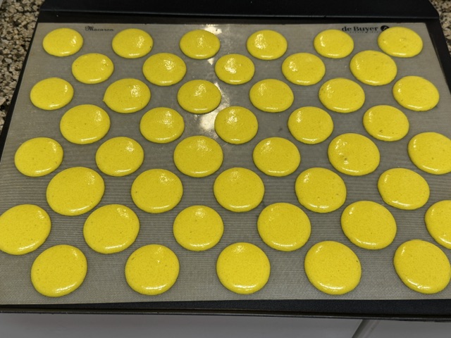 Des coques jaunes pochées sur une plaque, prêtes à enfourner 