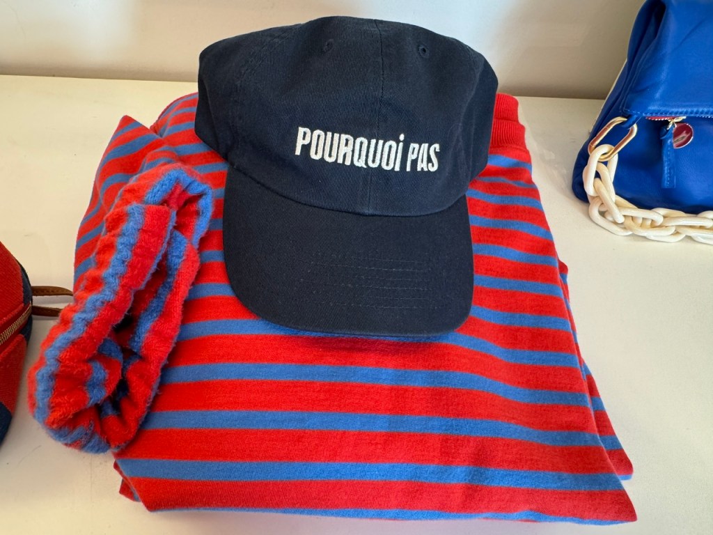 Chemise à rayures bleu et rouge, avec un chapeau bleu qui dit « Pourquoi pas »