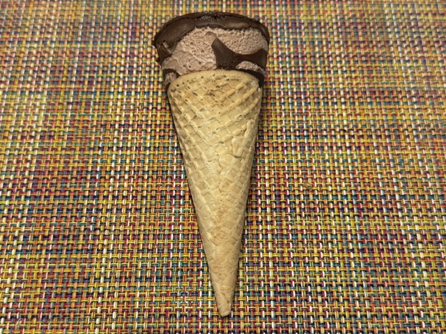 Cornet de glace Nutella déballé -- en haut du cornet, une certaine partie de glace se tient, avec un "chapeau" de chocolat parfumé à la Nutella.