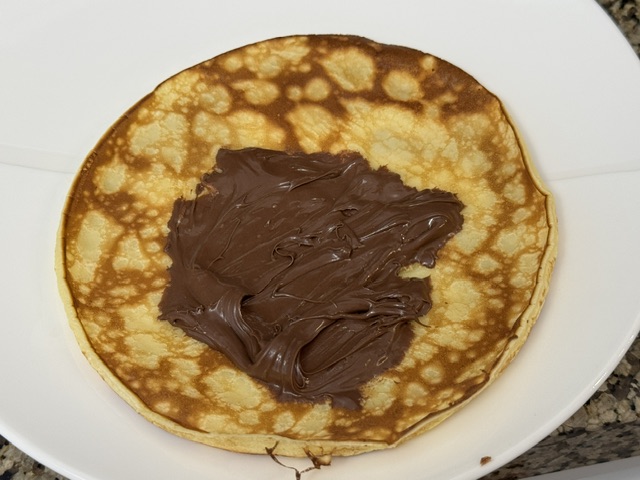 Nutella étalé sur la crêpe, peut-être plus que la moitié 