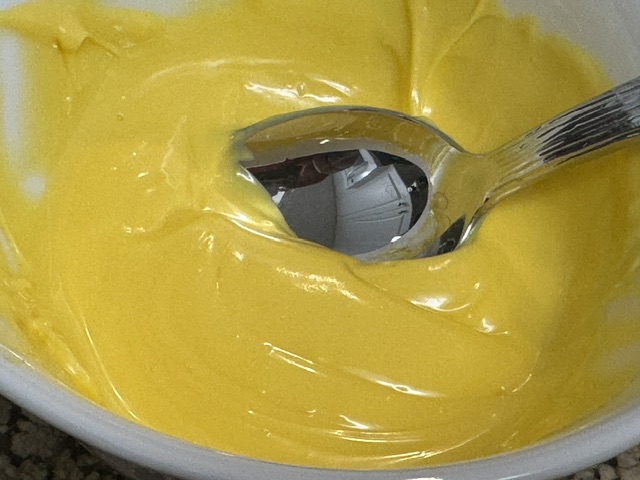 Chocolat coloré jaune bien fondu, avec une cuillère en métal dans le bol